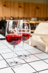 Two wine glasses filled with red wine, served on a white table in restaurant or bar.