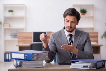 Young male employee unhappy with excessive work in the office