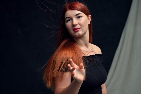 high resolution studio photo of redhead girl with long hair posing on dark background