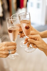 Beautiful female hands are holding glasses of champagne or rose wine. Close-up. Women clink glasses. New Years celebration, event or party. Soft focus. Human hands. Vertical shot