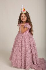 beautiful happy brown-haired girl with curly hair in a pink dress dancing birthday