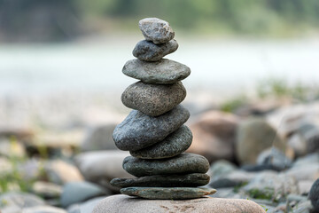Fototapeta na wymiar Pyramid of round gray stones on the bank of a mountain river. Zen and harmony concept.Stone tower