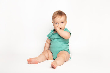 cute Caucasian one year old baby sucks thumb and scratches his first teeth. toddler boy teasing on...
