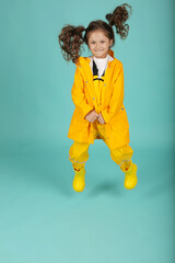a beautiful happy brown-haired girl with curly hair in a yellow jacket and overalls jumps
