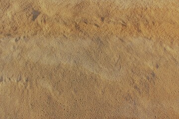 Beach surface texture of different shades of gold colors in uneven rough sand