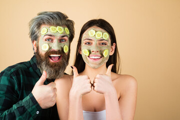 Couple with thumb up with spa mask, beauty concept portrait. Face clay mask spa. Man and woman with cosmetic mud facial procedure, spa health concept. Skin care beauty treatment.