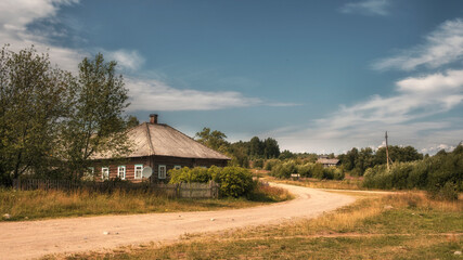 An old village with wooden houses and a dirt road in the north of Russia in summer