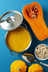 Concept of tasty food with pumpkin soup on blue background