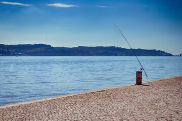 Fishing Rod On Colorful Metal Barrel Located on Pier of Lisbon in Portugal.