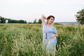 Fototapeta premium Beautiful young woman in summer in a wheat field
