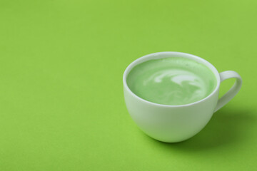 Cup of matcha latte on green background