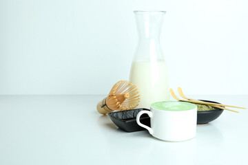 Matcha latte and accessories for making on white table