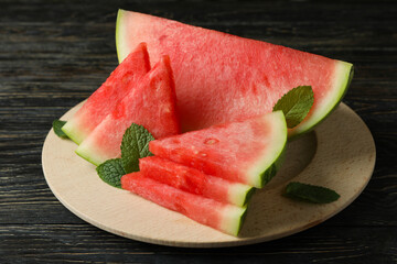 Wooden board with watermelon slices and mint leaves