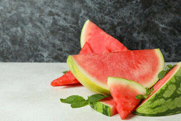 Watermelon slices and mint leaves on white textured table