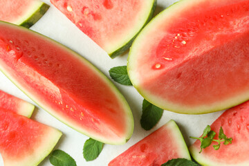 Watermelon slices and mint leaves on white textured table