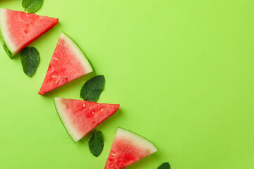 Juicy watermelon slices and leaves on green background