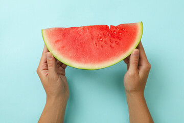 Female hands hold watermelon slice on blue background