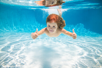 Underwater child swim in water swimming pool has fun under water on summer vacation.