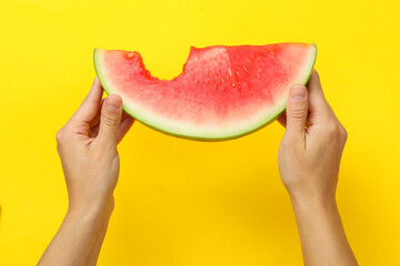 Female hands hold watermelon slice on yellow background