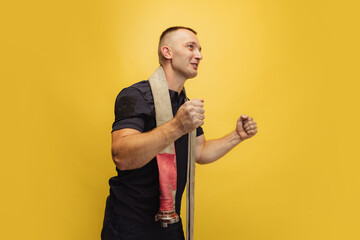 One brutal smiling man posing with fire hose over his neck on yellow studio background. - Powered by Adobe