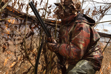 the hunter looks out from a shelter made of camouflage nets