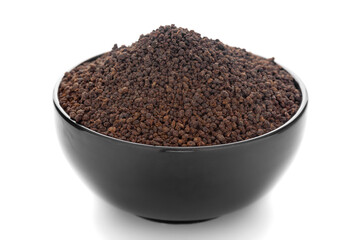 Close-Up of organic black dry cut leaves of tea (Camellia sinensis)  in black ceramic bowl over white background