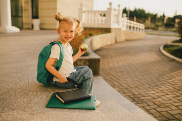 Cute little schoolgirl with school bag on a street