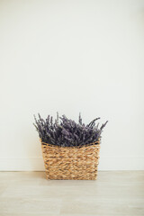 Basket with lavender standing near white wall. Place for text.