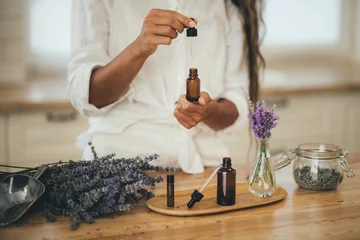 Fotobehang Young woman applying natural organic essential oil on hair and skin. Home spa and beauty rituals. © polinaloves