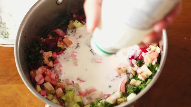 pouring buttermilk and curdled milk and kefir into vegetables chilled beet soup