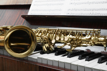 Beautiful saxophone on piano keys. Musical instruments
