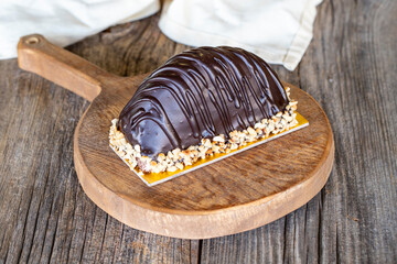 Chocolate dessert on a wooden background. Cake filled with banana and cream