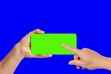 Female hand taping on green chroma key screen of modern smartphone, the device is located frontally flat lay