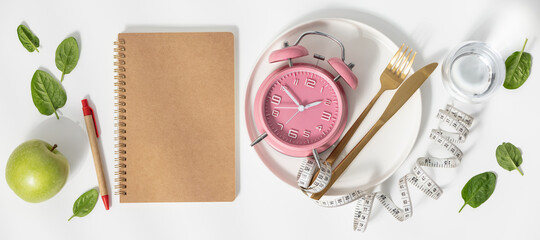 Composition with cutlery, measuring tape, blank paper notebook and alarm clock on color background....