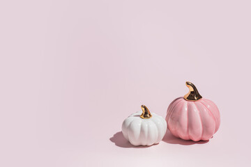 Two decorative ceramic pumpkins on pink background in hard light with copy space. - 451375911