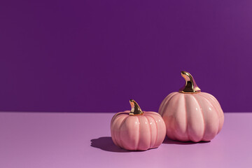 Two pink decorative pumpkins on lilac and purple background in hard light with copy space. - 451375957