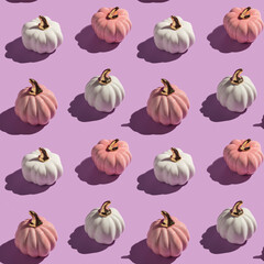 Seamless pattern made with pink and white decorative autumn pumpkins flat lay on lilac background in hard light. - 451375990