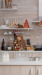 Fototapeta na wymiar Empty xmas decorated culinary kitchen with nobody in it is ready for traditional christmas celebration. On table standing traditional homemade cookie dessert ingredients with milk glass