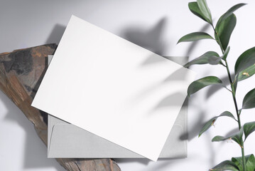 Mockup white greeting paper card with envelope and green leaf. for mock-up design template..