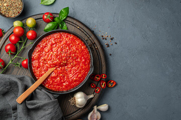 Italian marinara sauce and ingredients on a dark background.