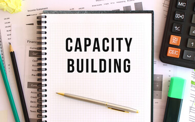 Notepad with text CAPACITY BUILDING on the office desk, near office supplies. Business concept.