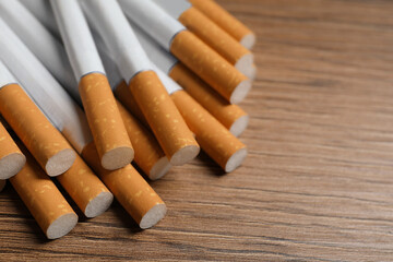 Pile of cigarettes on wooden table, closeup. Space for text