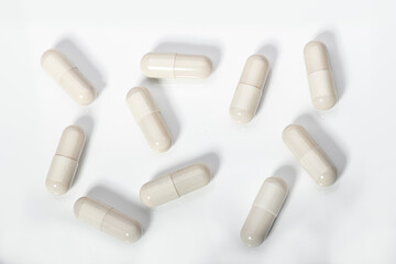 White capsules of medication on a white acrylic background