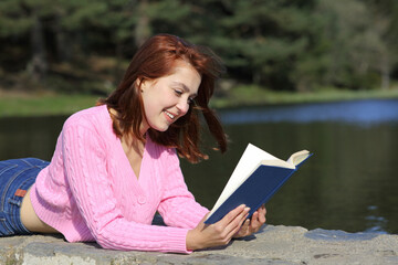 Obraz premium Woman reading a book lying in the mountain