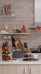 Empty xmas decorated kitchen with nobody in it is ready for christmas morning dessert. On table baked cookie dessert with cup of coffee waiting for guest during winter holidays