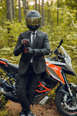 Obraz premium Handsome biker with helmet and dark motorcycle in forest