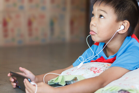Portrait image of 7-8 years old child. An Asian boy using mobile smart phone to learning and playing social media.