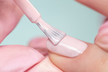 Close up process of applying pink varnish. Woman in salon receiving manicure by nail beautician. Pink Nail polish and brush, macro. - obrazy, fototapety, plakaty