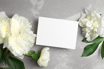 Fototapeta na wymiar Greeting or invitation card mockup with copy space and white peony flowers on grey