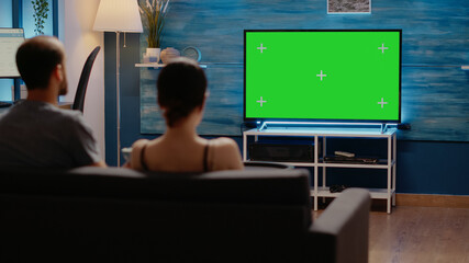 Green screen on television at home in living room used by young man and woman for copy space design...